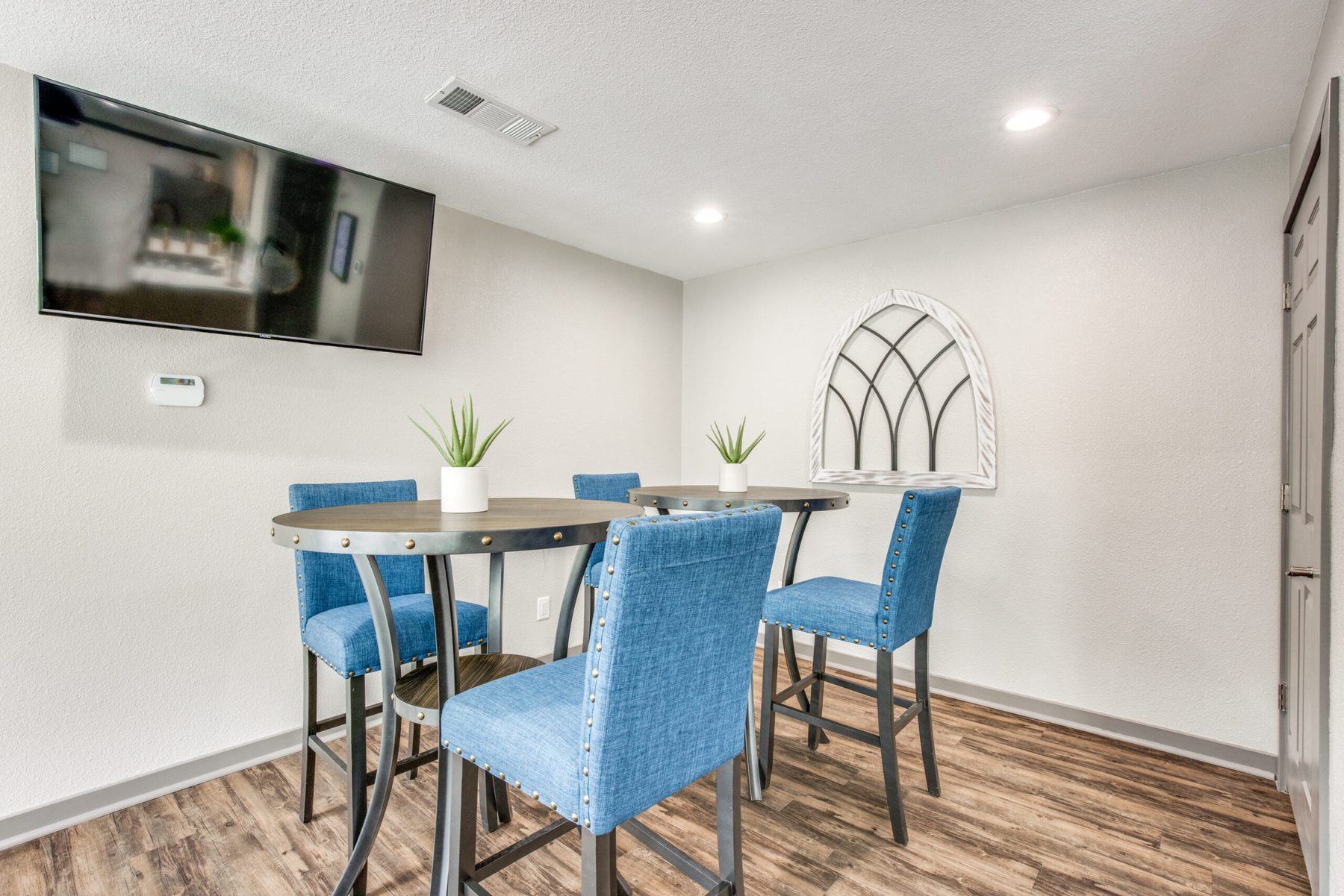 Dining area with blue upholstered chairs and an arched window